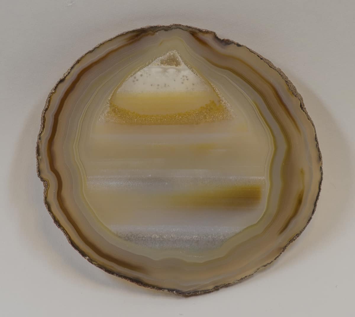 Une tranche d'agate polie : des bandes concentriques brunes en bordure, des lits horizontaux au centre.
